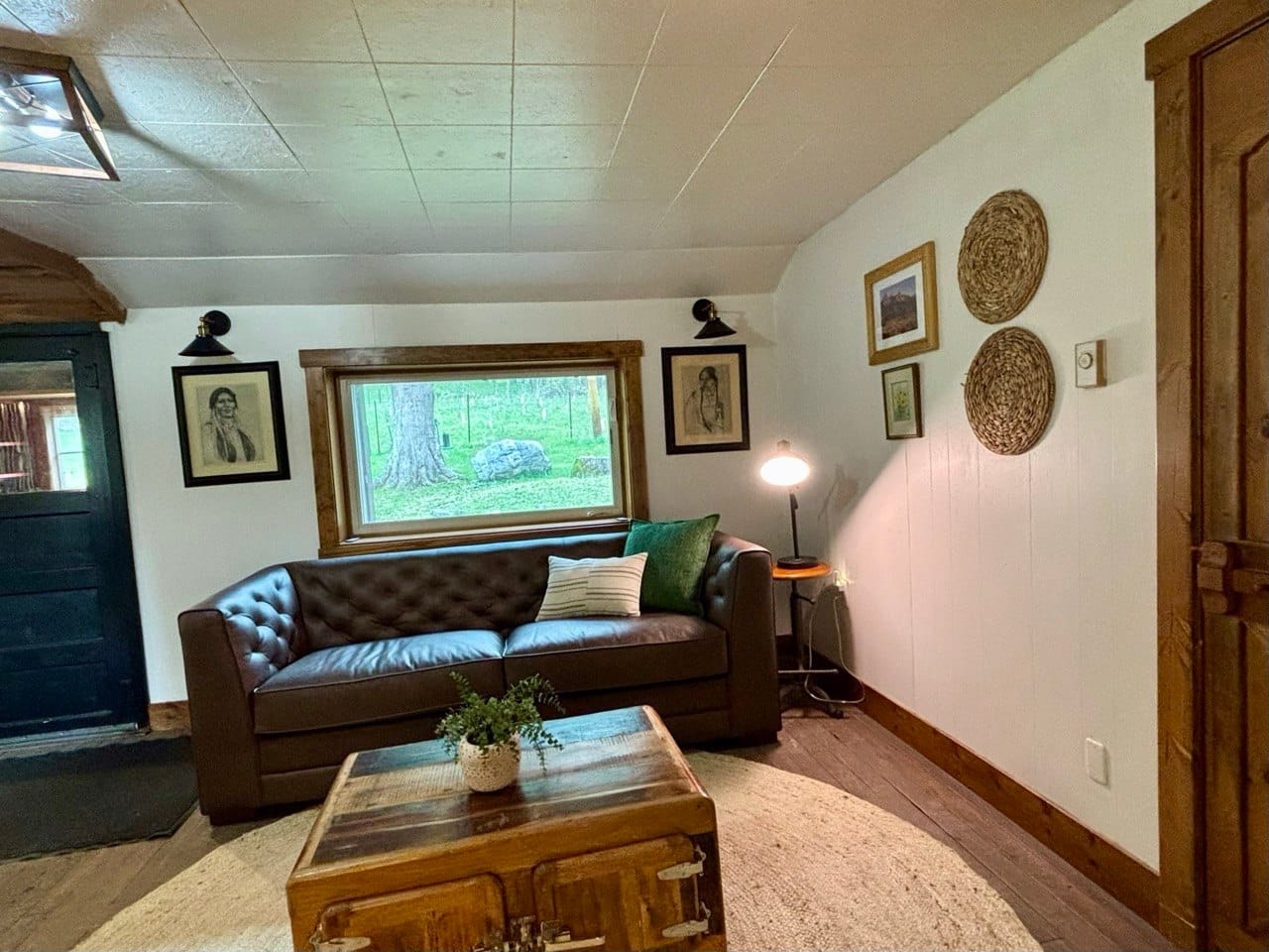 Living room — warm wood, comfortable couch, and windows to the woods